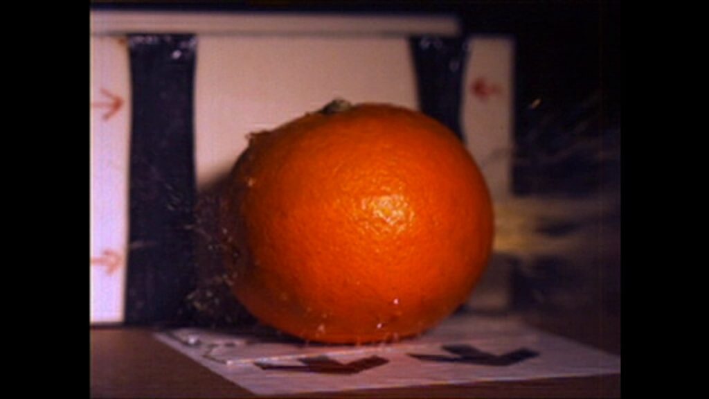 An orange shot with a compound bow. Filmed in super high speed.
